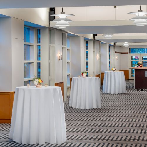 A bright classroom or library with blue shelves, a white pillar, and round tables; soft lighting and a calm, organized space.