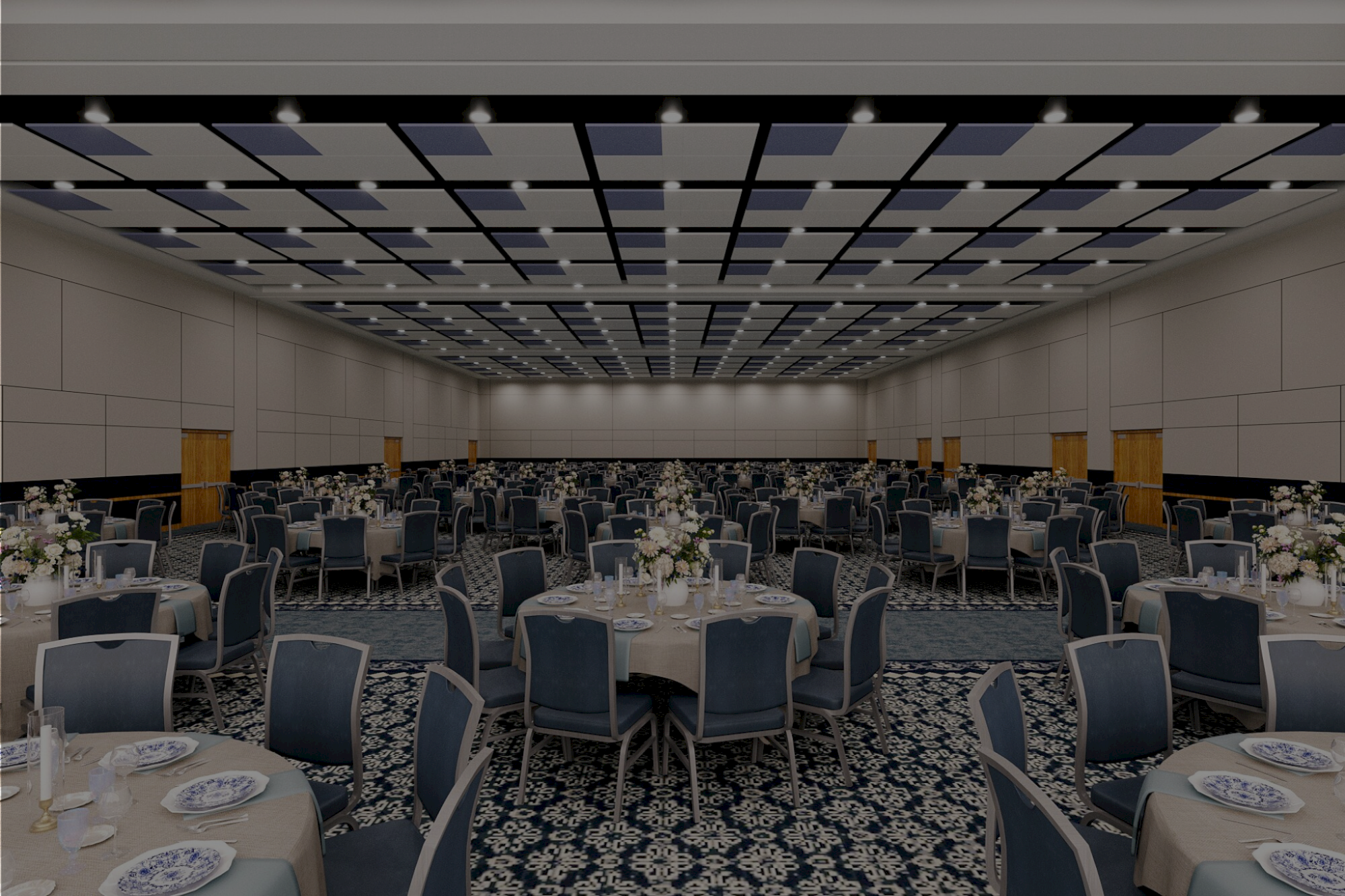 A large banquet hall set for a formal event, with round tables, blue chairs, white tableware, and floral centerpieces under a patterned ceiling.