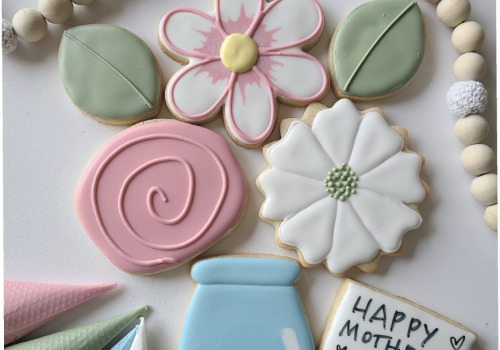 A colorful display of iced cookies in floral, leaf, and jar shapes for a sweet Mother&rsquo;s Day celebration.