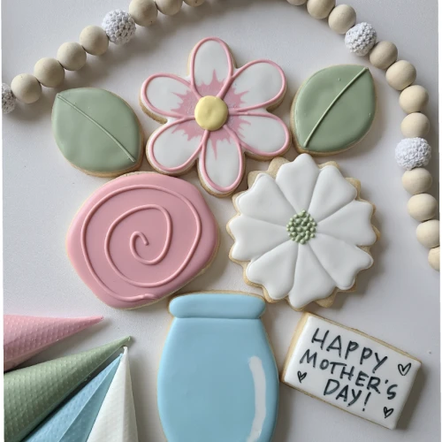 A colorful display of iced cookies in floral, leaf, and jar shapes for a sweet Mother&rsquo;s Day celebration.