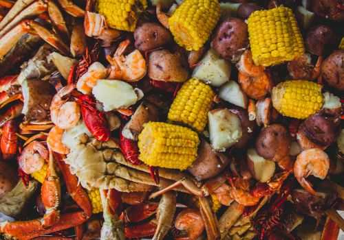 A seafood boil with shrimp and crawfish, corn on the cob, potatoes, and sausages piled together, ready to eat.
