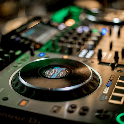 A close-up of a studio audio mixer with a large circular control knob and illuminated buttons.