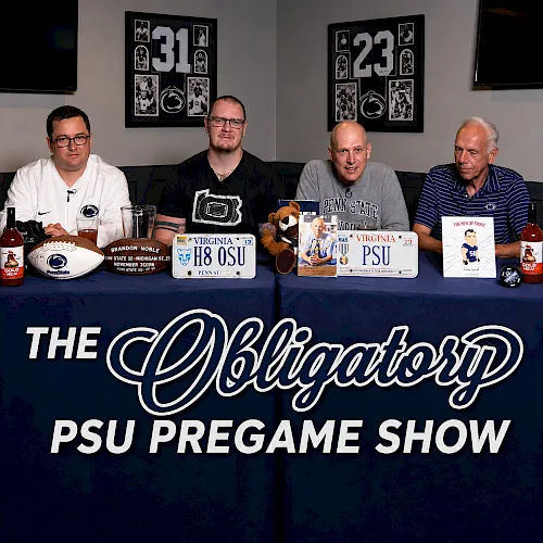 Four men at a table for the “PSU Pregame Show,” with football-themed signs and bottles on the blue banner.